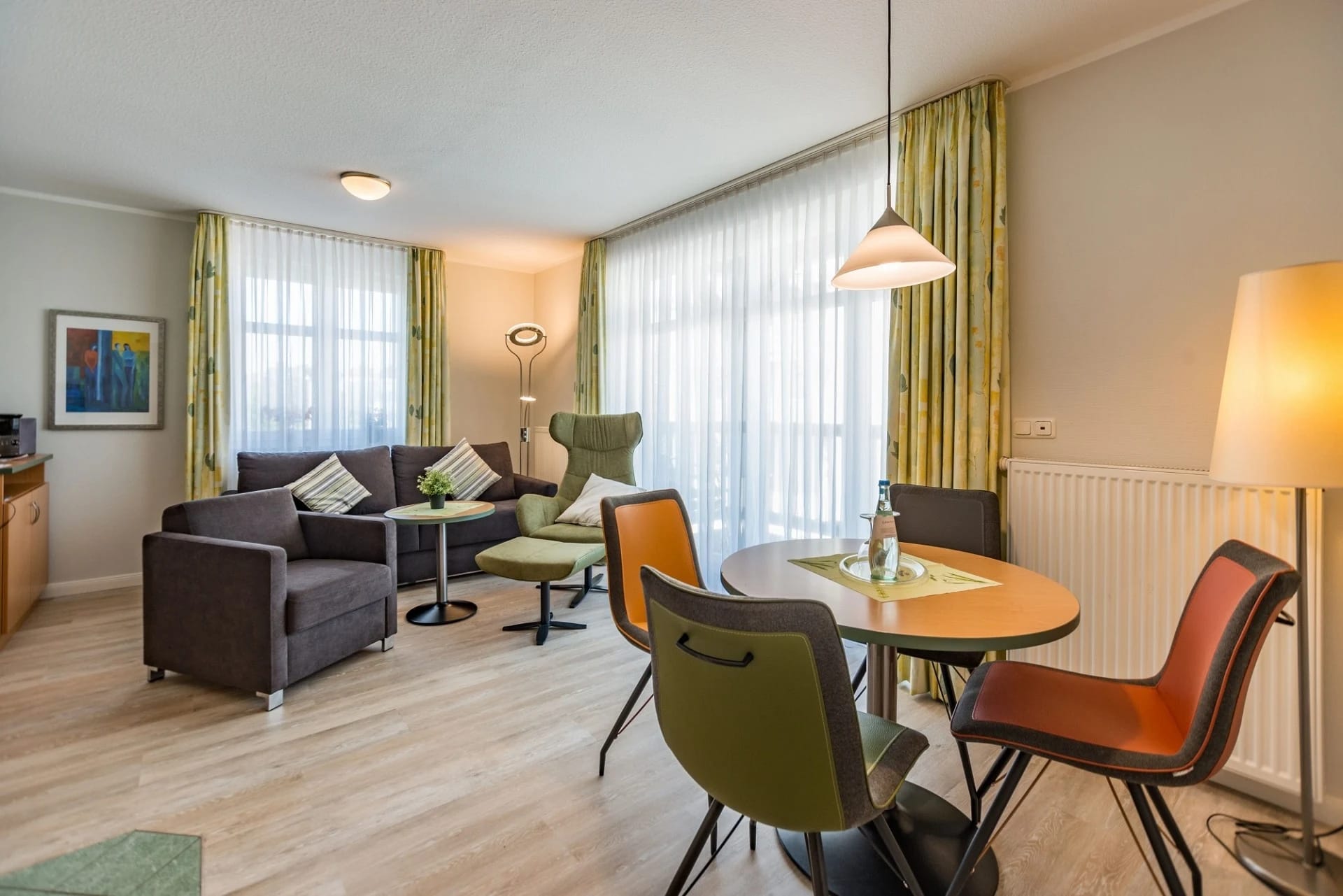 Wohn- und Essbereich eines Apartments mit Sofa, Sesseln und Esstisch