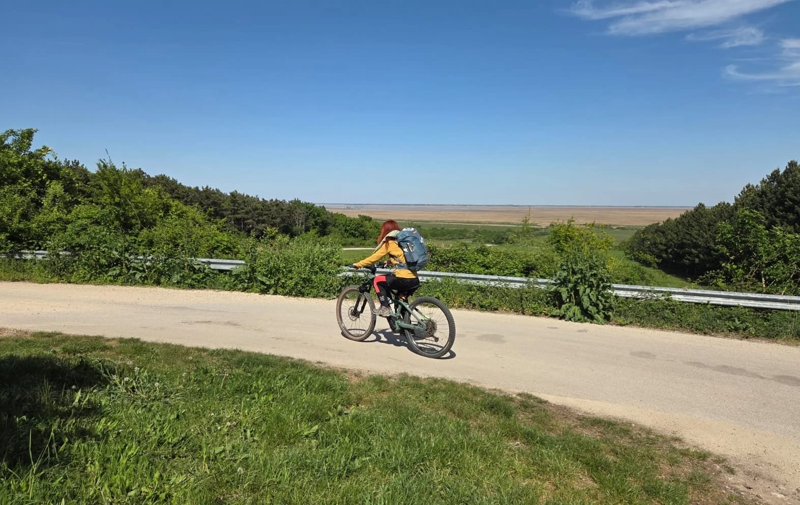 Karin fährt mit dem E-Bike auf einer Landstraße durch grüne Hügel
