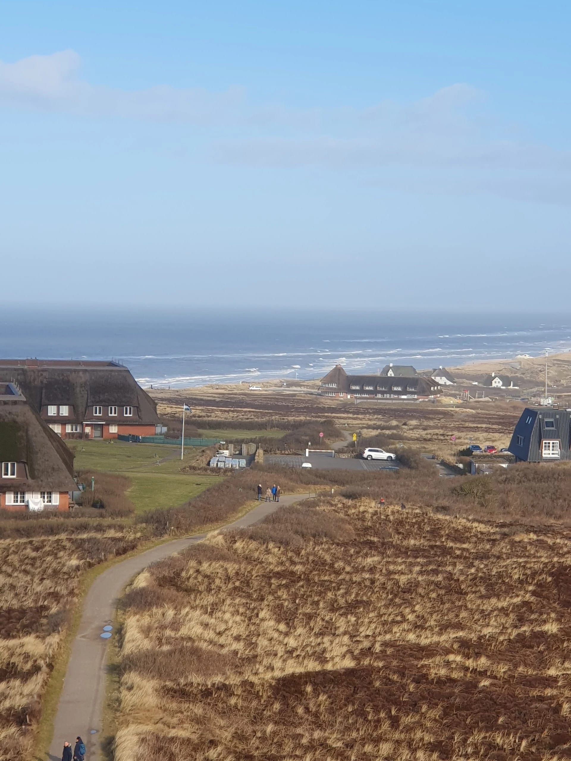 Küstenlandschaft mit Reetdachhäusern und Blick aufs Meer