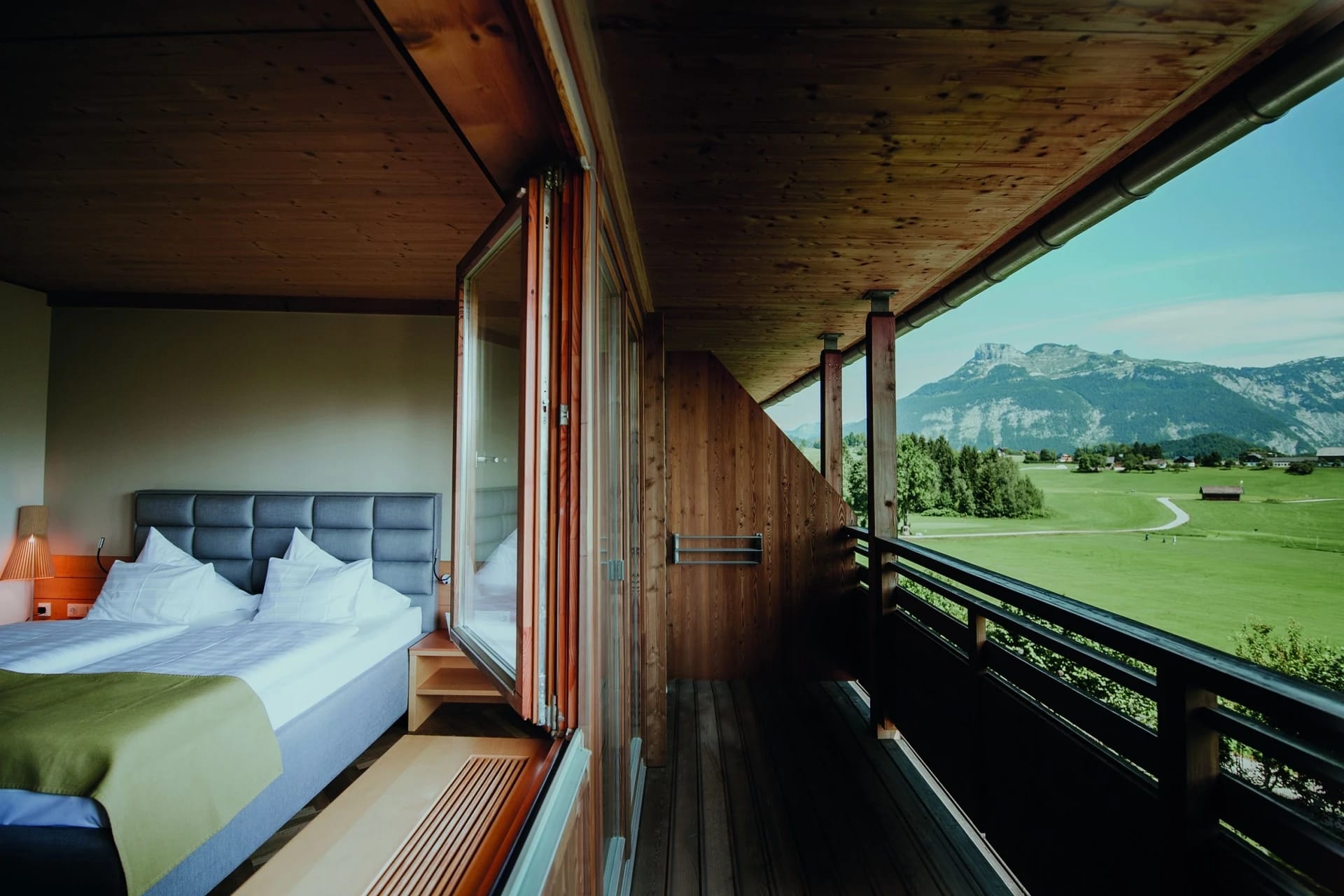 Hotelzimmer mit offenem Holzpaneel und Panoramablick auf Bergwiese