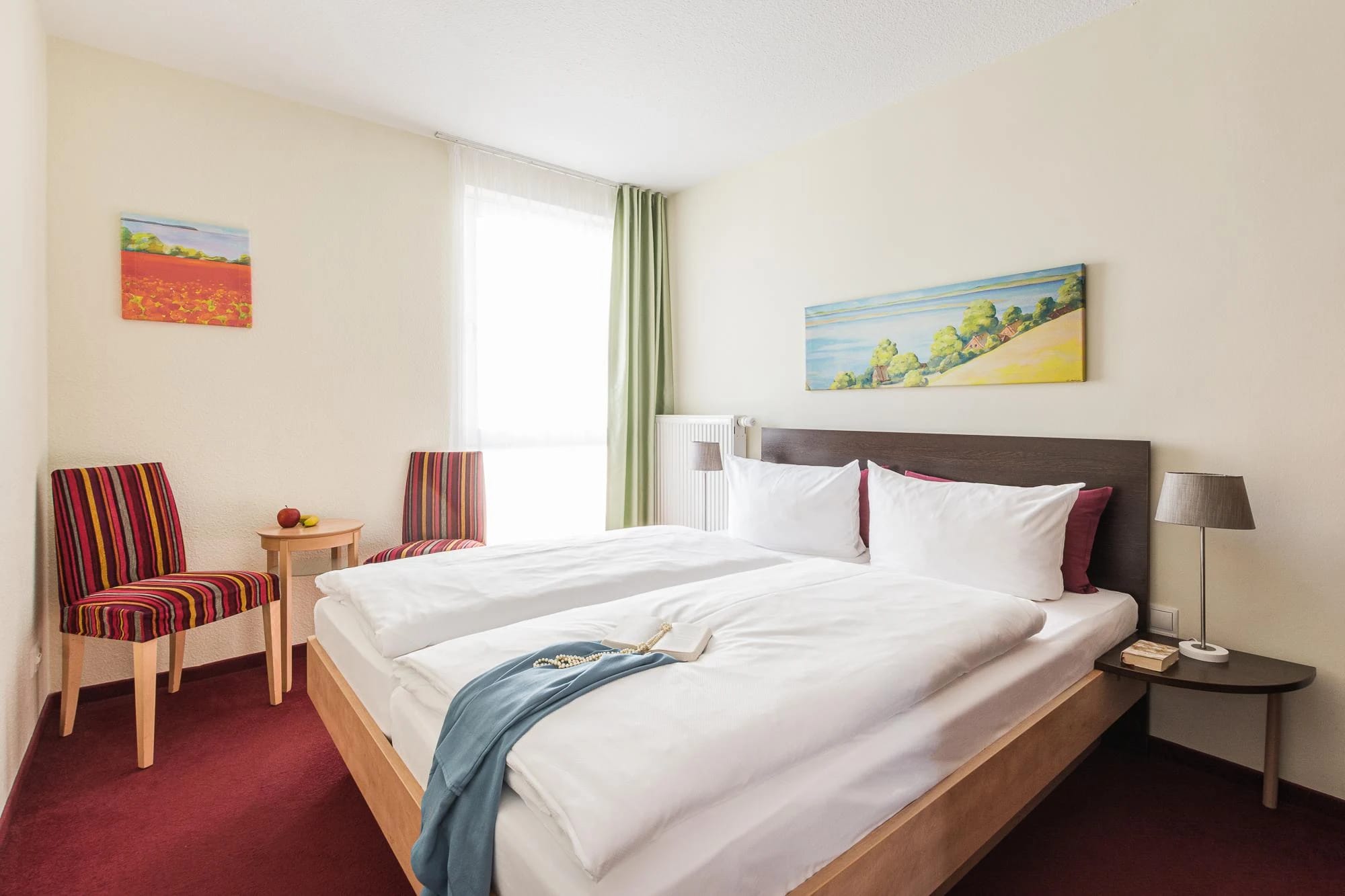 Doppelzimmer mit Doppelbett und maritimen Wandbildern