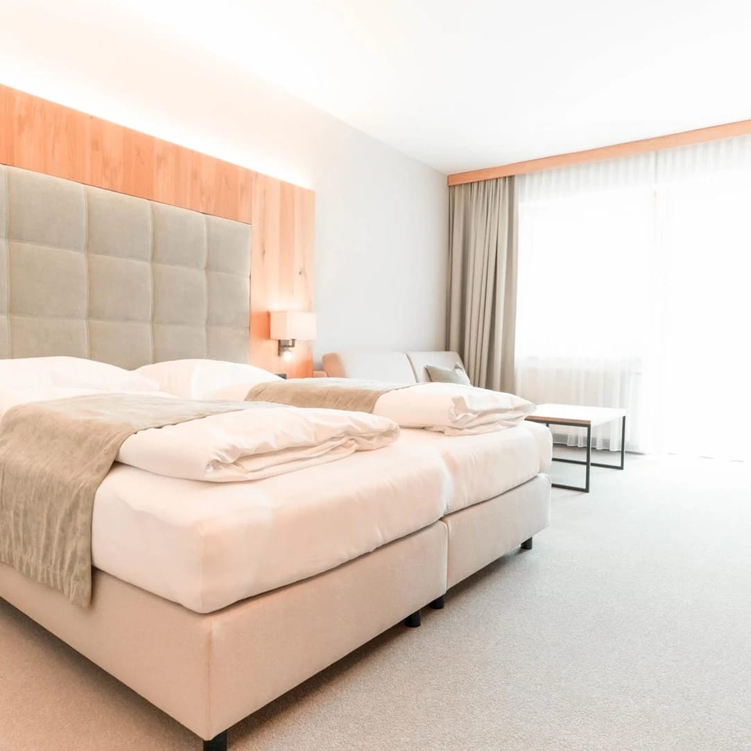 Modernes Hotelzimmer mit Doppelbett und Sitzecke in warmen Tönen