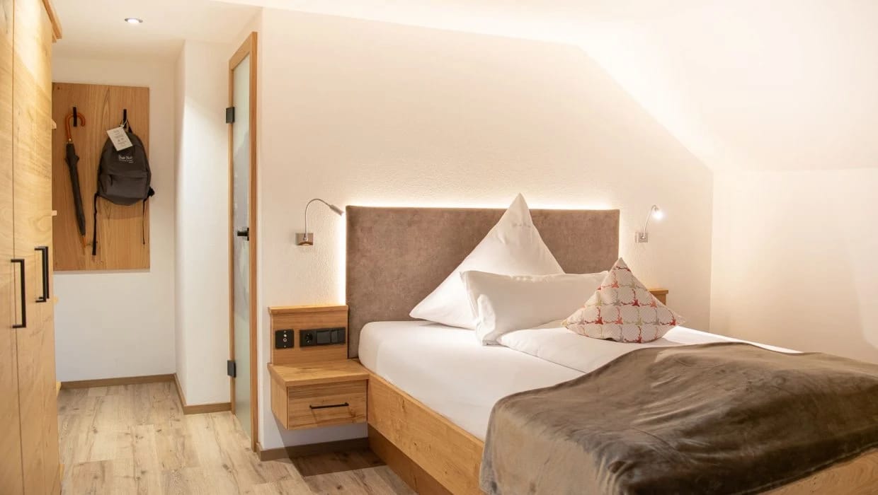 Helles Zimmer mit Doppelbett und Garderobe aus Holz