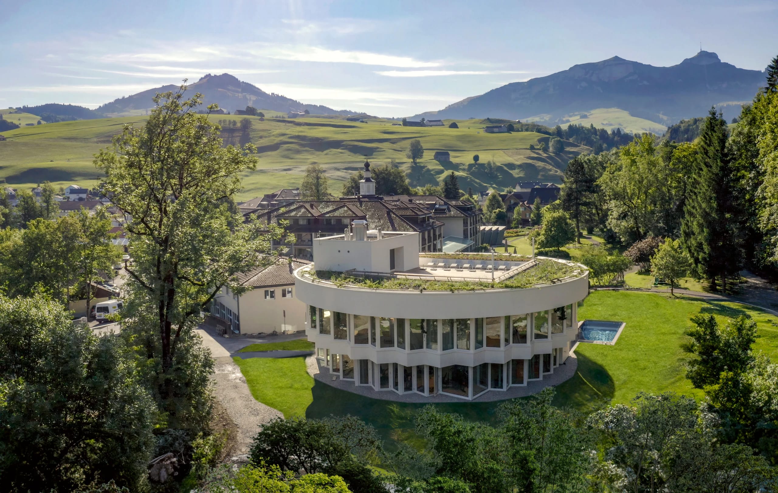 Luftaufnahme des runden Spa-Pavillons (Lodge) mit Blick auf die Alpstein-Gipfel im Hintergrund