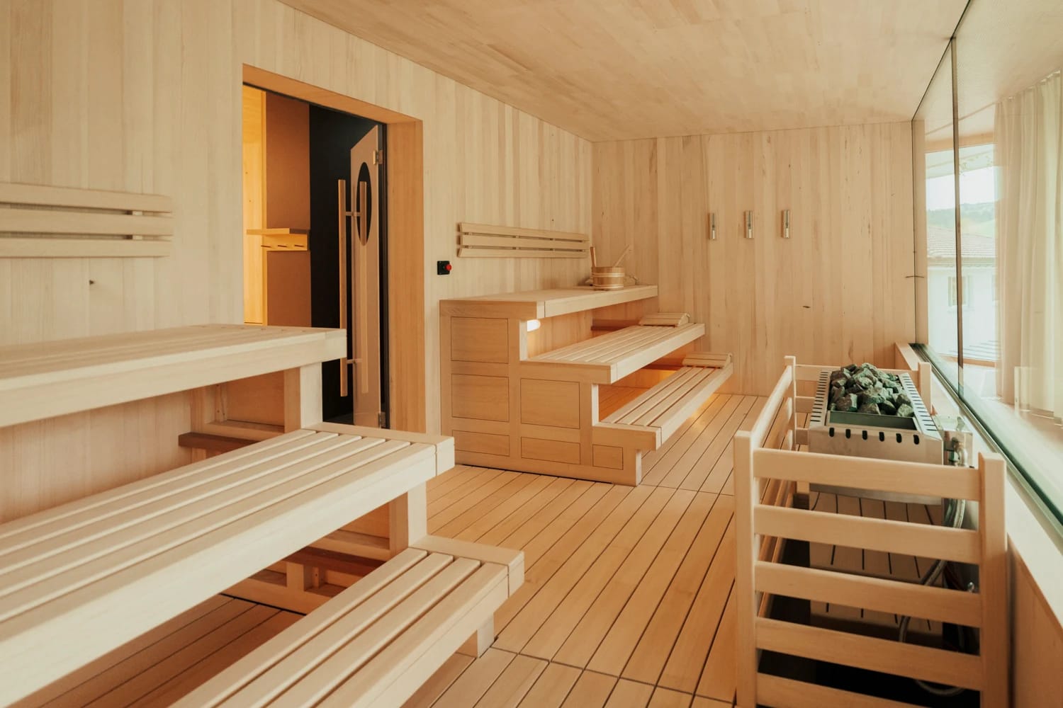 Finnische Sauna mit Holzbänken, Saunasteinen und Panoramafenster
