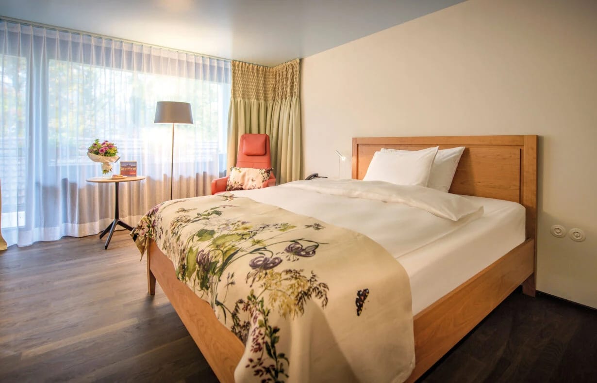 Hotelzimmer mit Doppelbett, Blumendecke und hellem Tageslicht