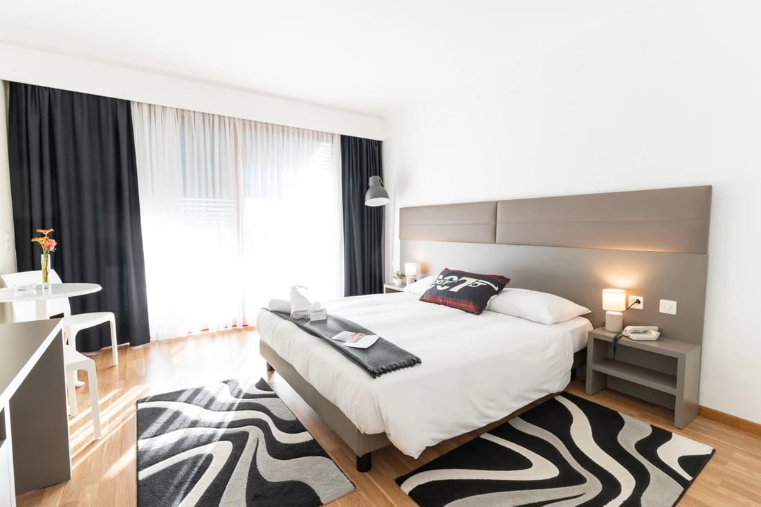 Helles Doppelzimmer mit Parkettboden, Sitzecke am Fenster und gemustertem Teppich