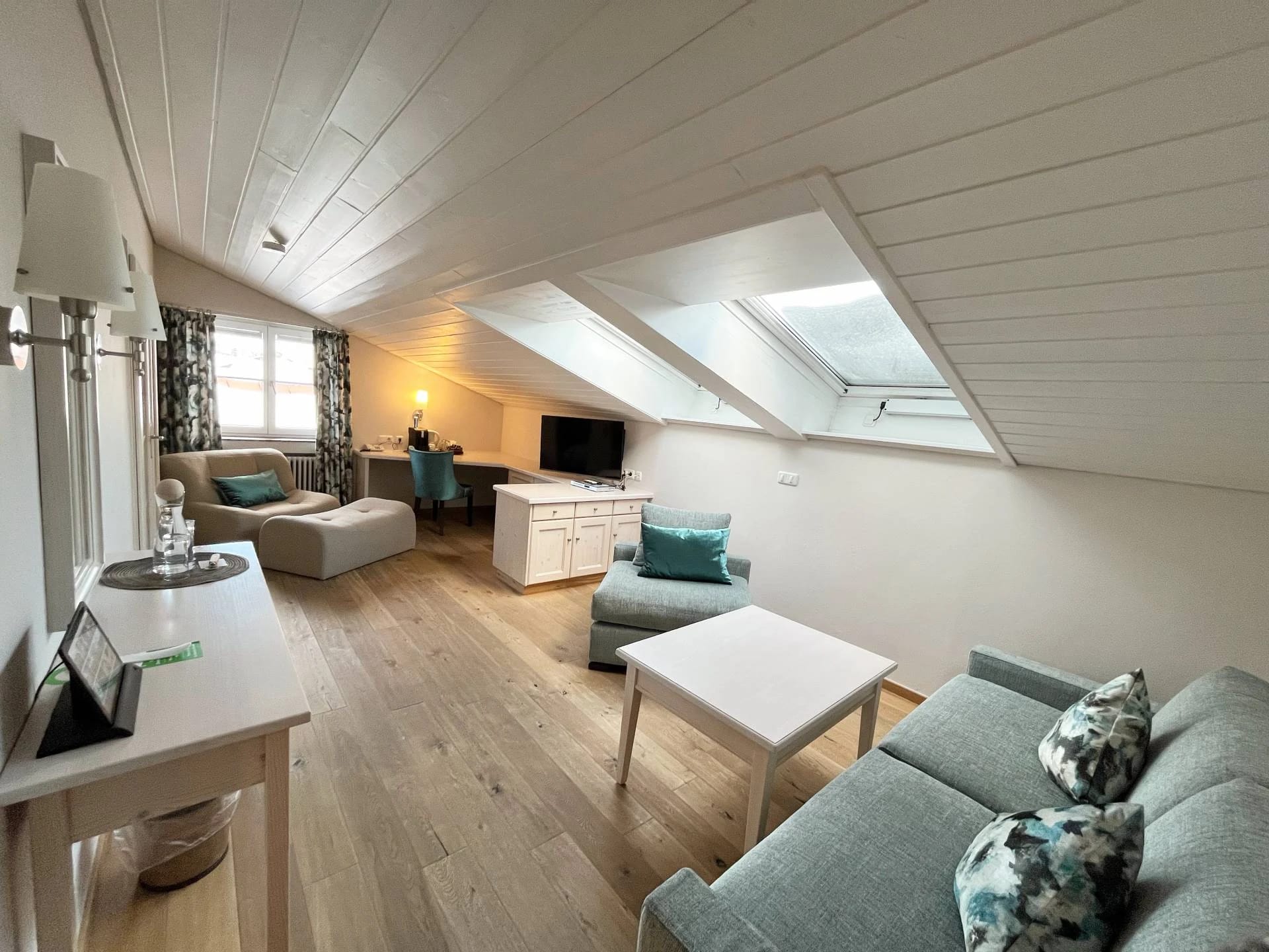Wohnbereich einer Suite unter der Dachschräge mit Sofas, Sesseln, Couchtisch und Dachfenstern