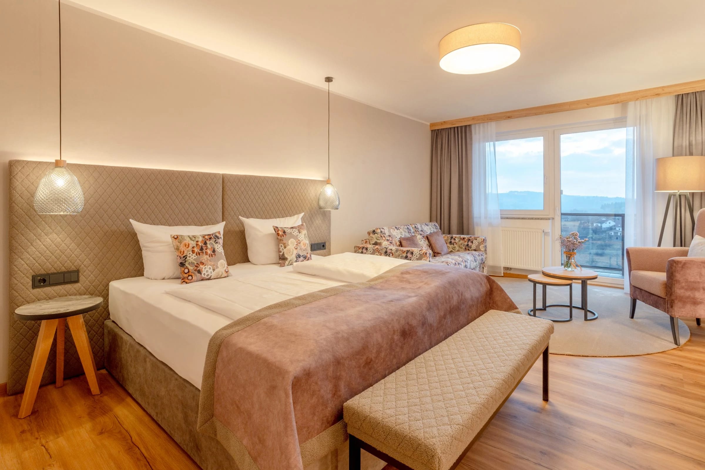 Helles Doppelzimmer mit Bettbank, Sitzecke und Fensterfront mit Landschaftsblick