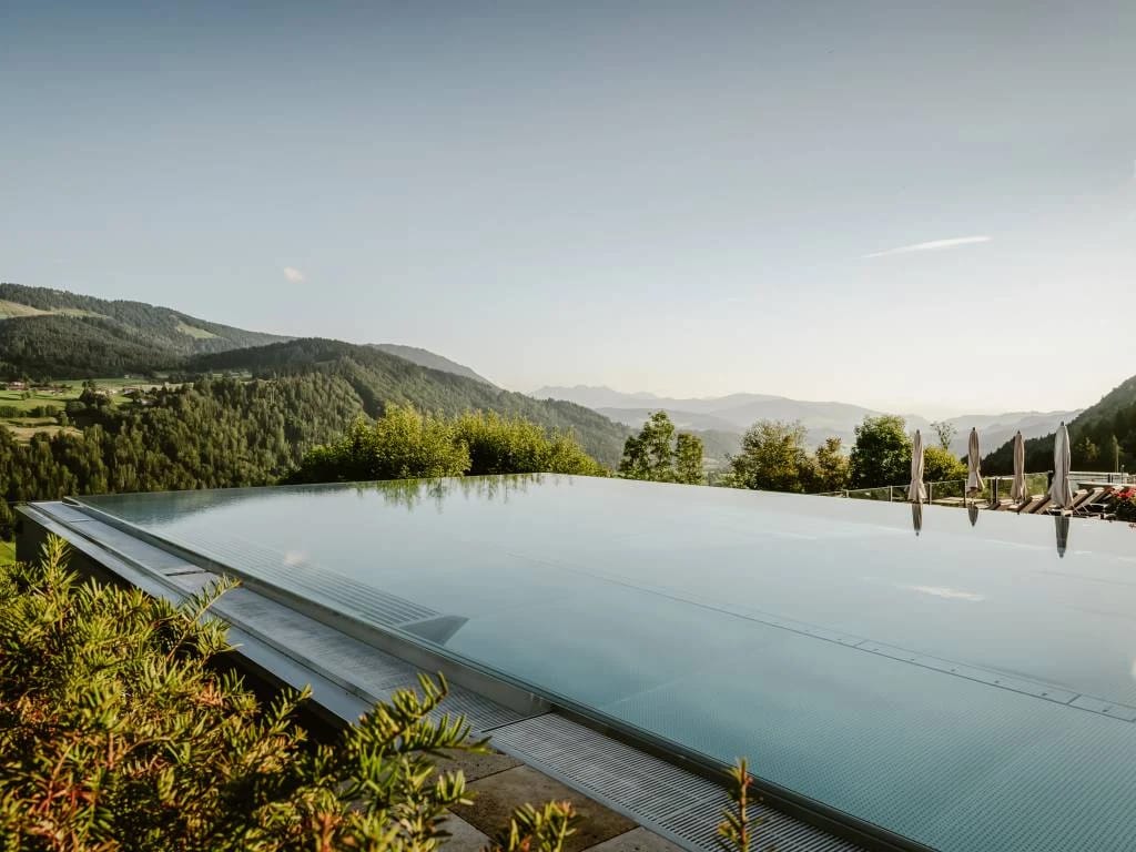 Infinity-Pool mit Blick über bewaldete Hügel und Berge