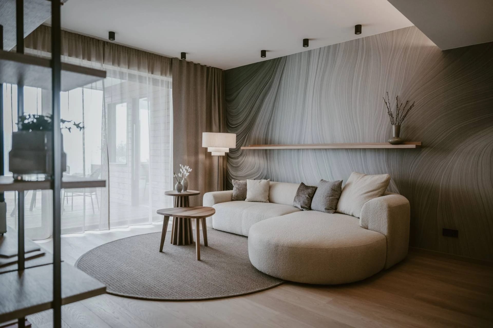 Wohnbereich einer Suite mit hellem Rundsofa, Beistelltisch und Holzboden