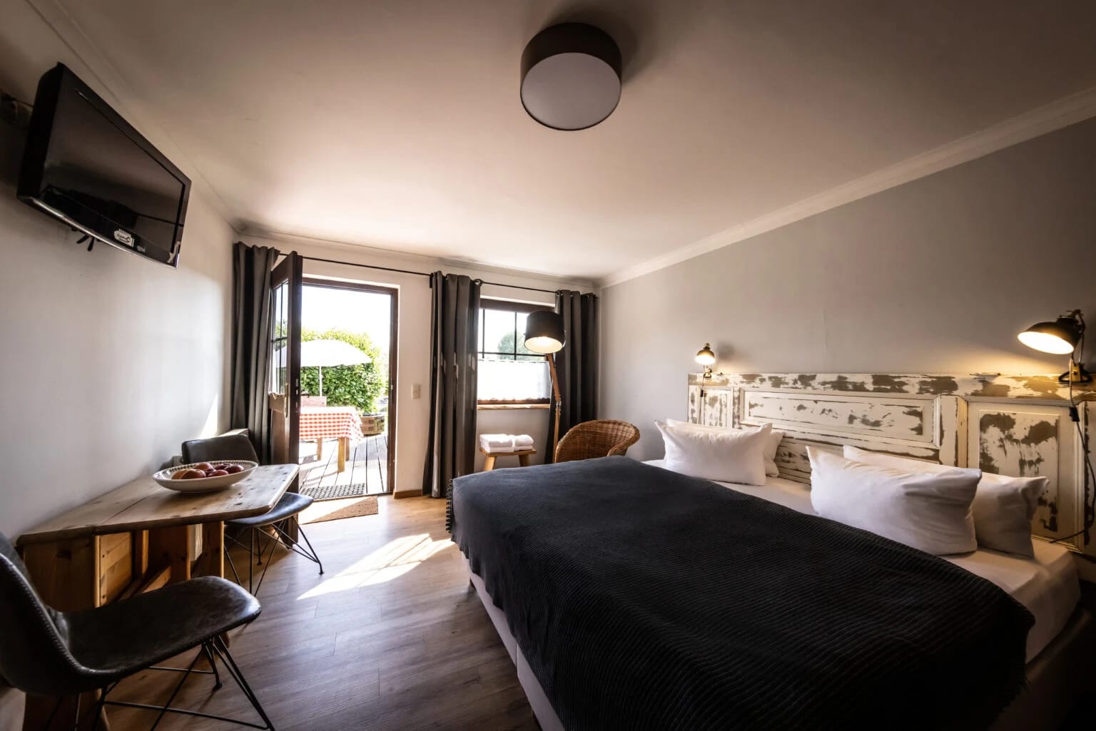 Doppelzimmer mit Doppelbett, Schreibtisch, Fernseher und Glastür zur Terrasse
