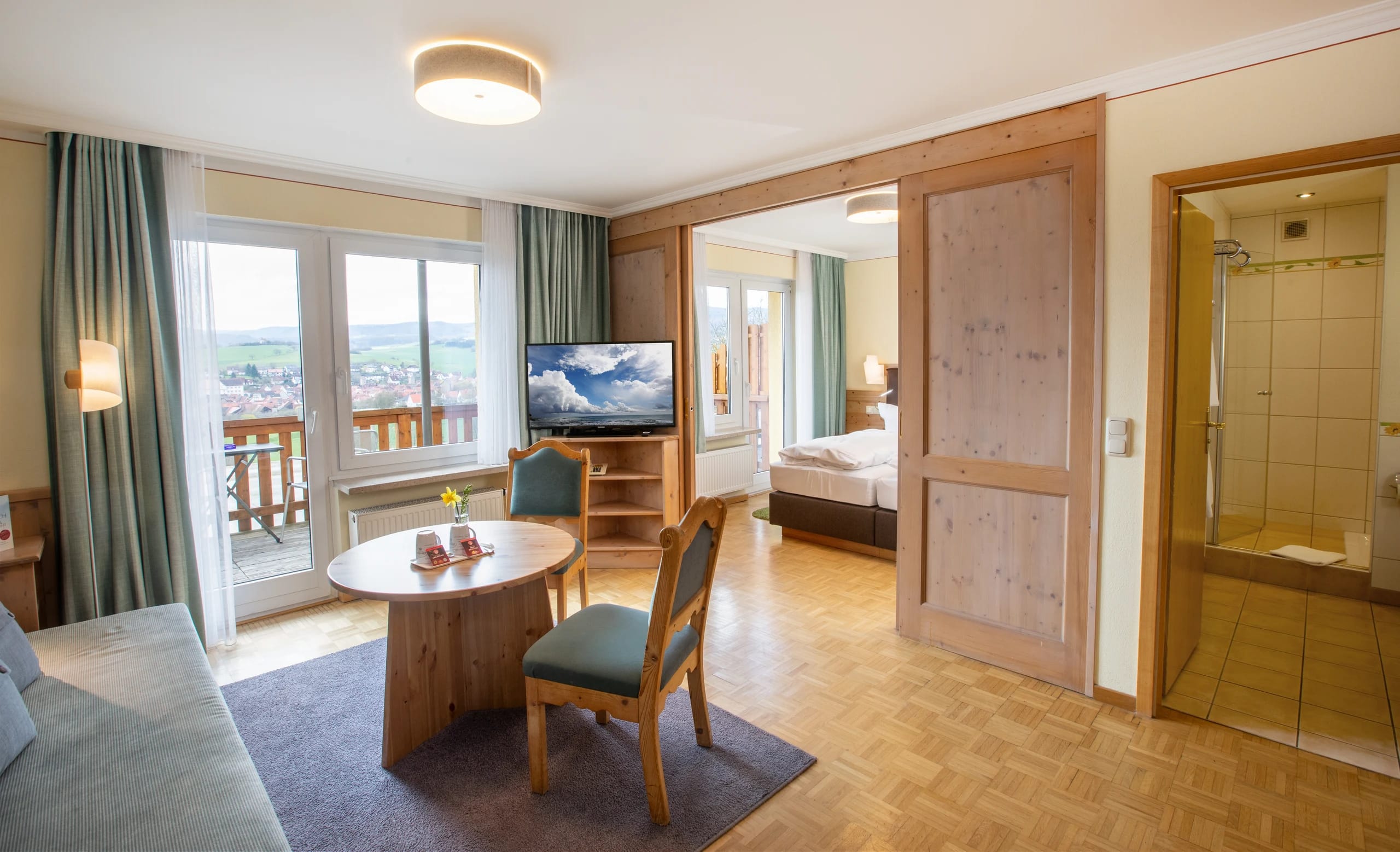 Juniorsuite mit Sitzecke, Balkontür und offenem Durchgang zum Schlafzimmer