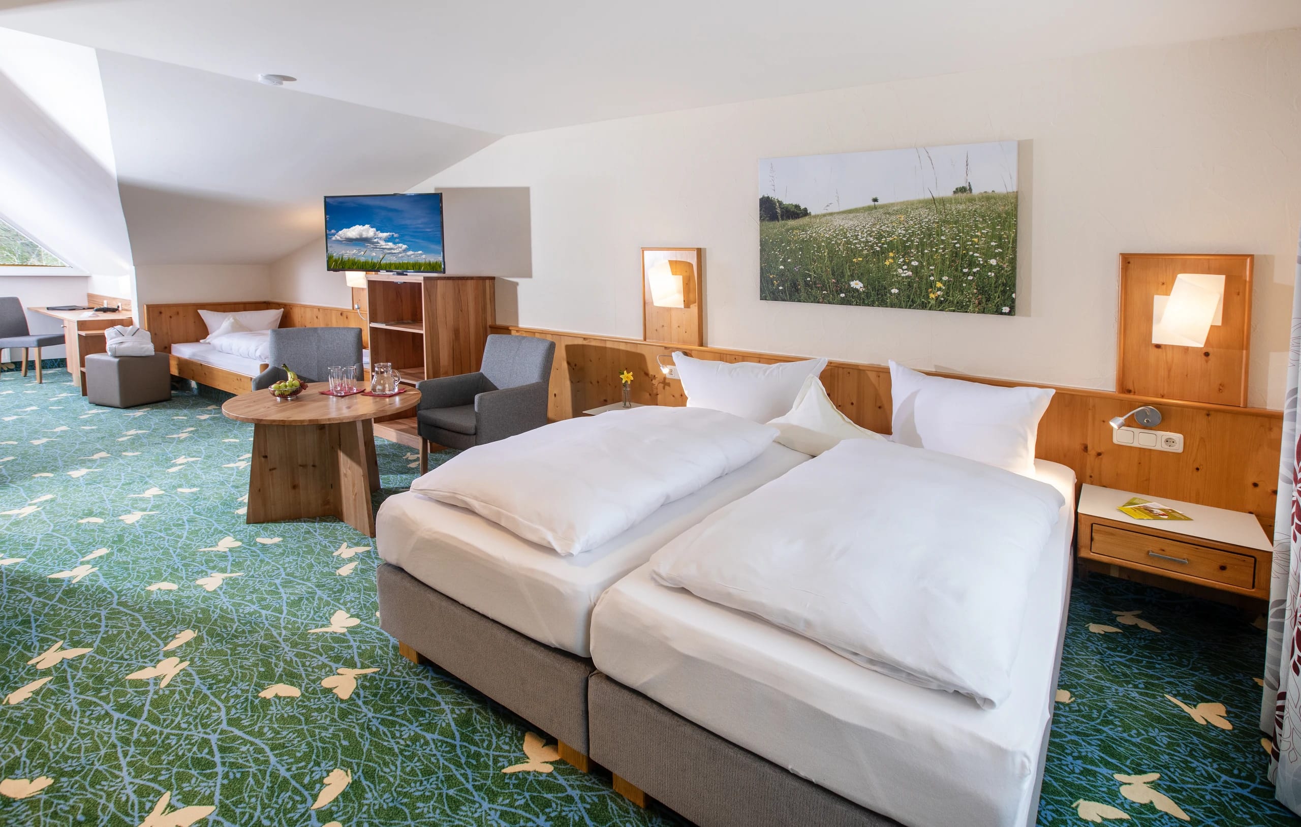 Geräumiges Zimmer mit Doppelbett, Sitzecke und grünem Teppichboden