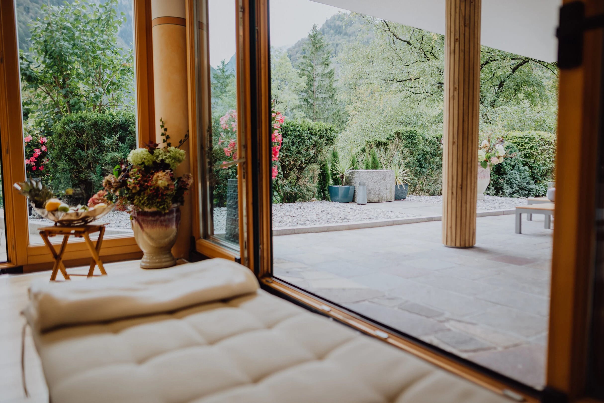 Ruheliege am bodentiefen Fenster mit Blick auf Garten und Berge