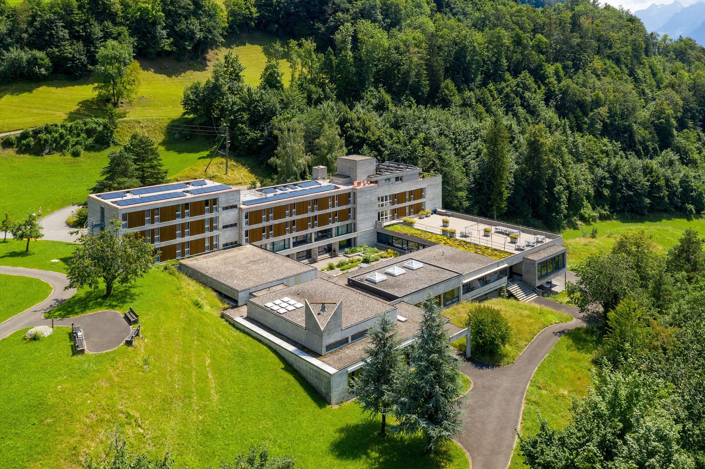Luftbild des Hauses mit Dachterrasse, umgeben von Wiesen und Wald