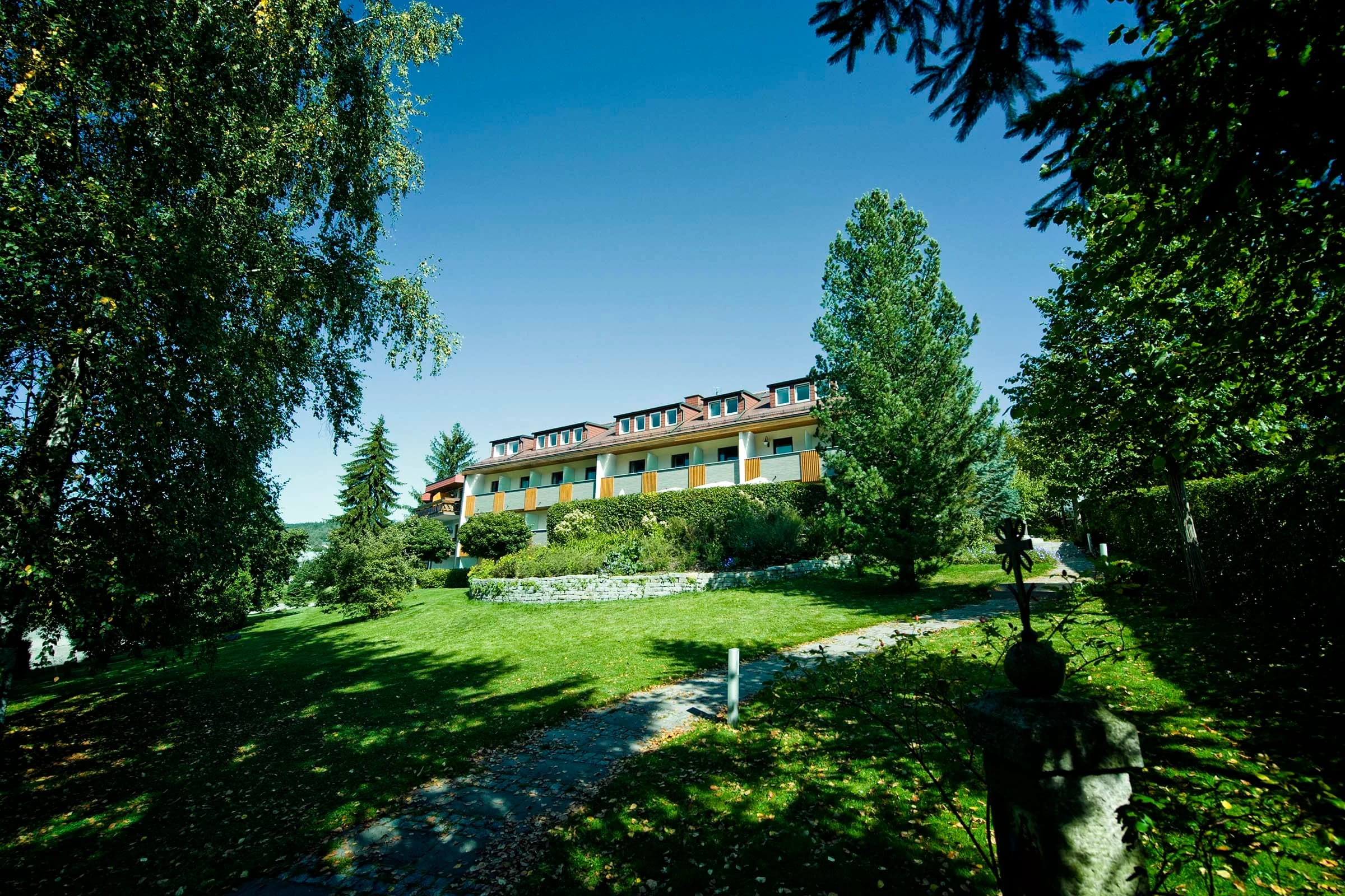 Außenansicht des Hotels mit weitläufigem Garten unter blauem Himmel
