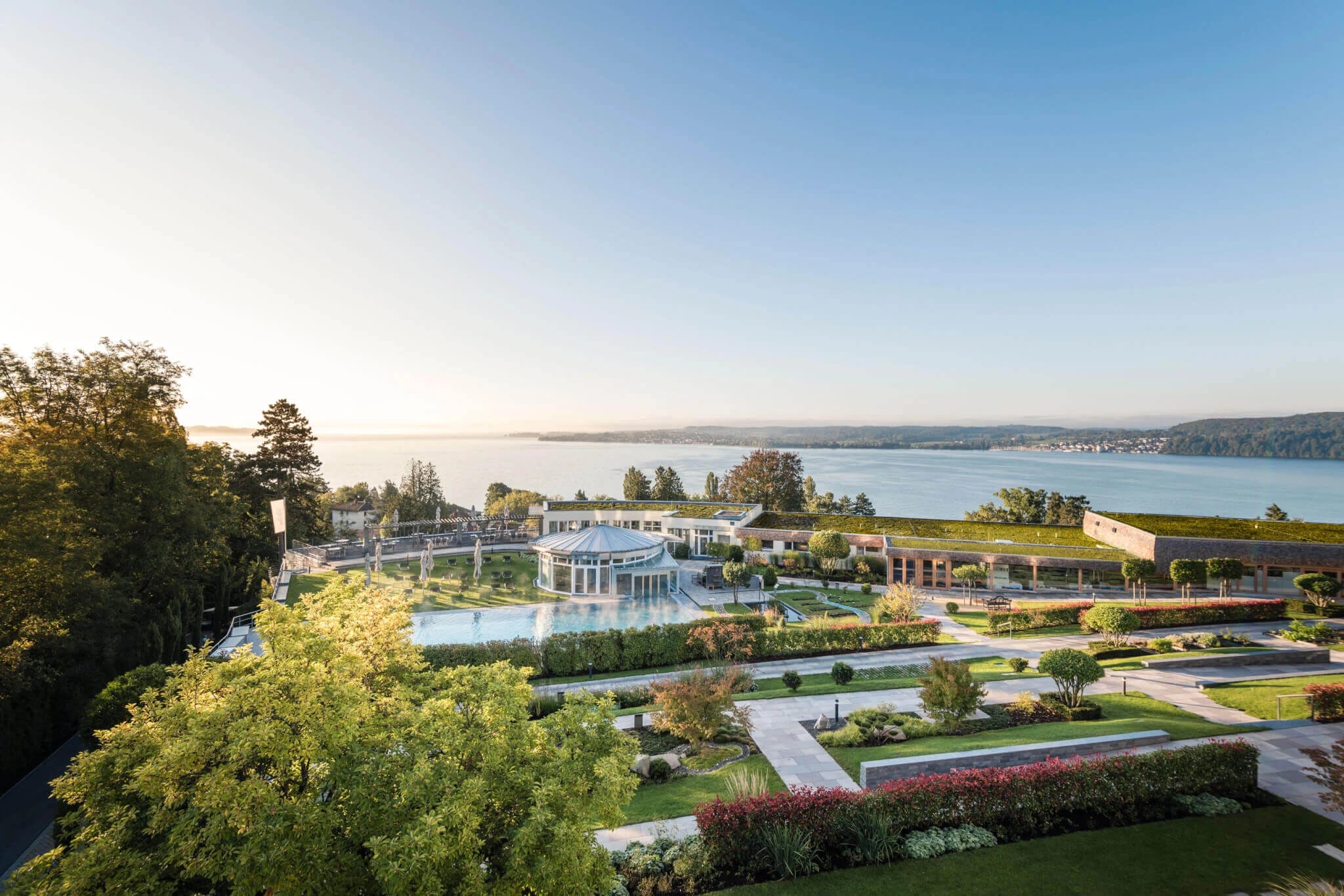 Morgenstimmung über der Gartenanlage mit Schwimmbecken, Pavillon und Blick auf den Bodensee