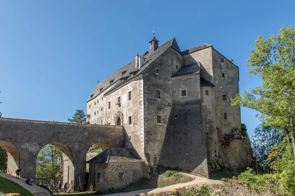 Burg Altpernstein mit steinerner Bogenbrücke vor blauem Himmel