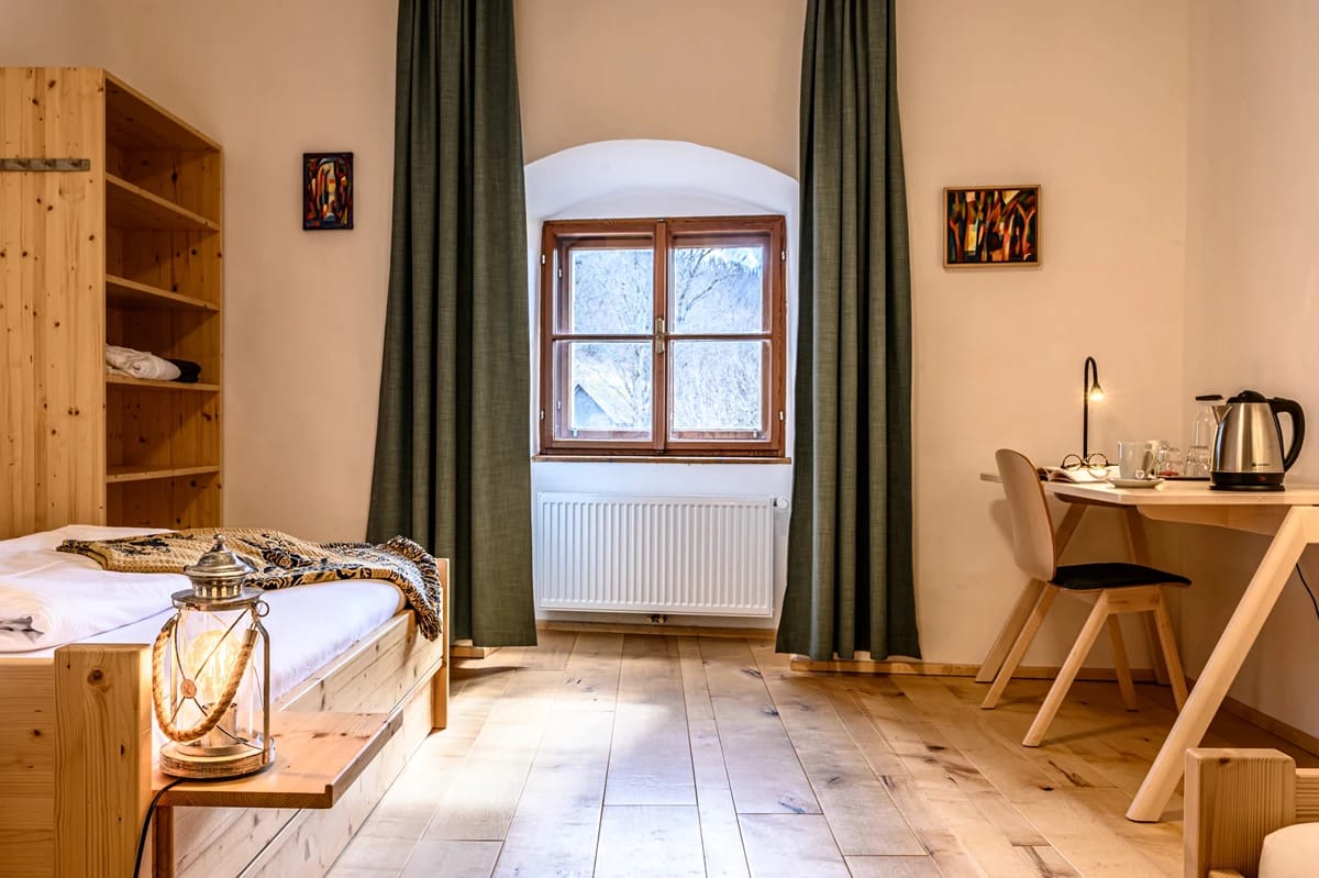 Gästezimmer mit Holzbett, offenem Regal, Schreibtisch und Sprossenfenster