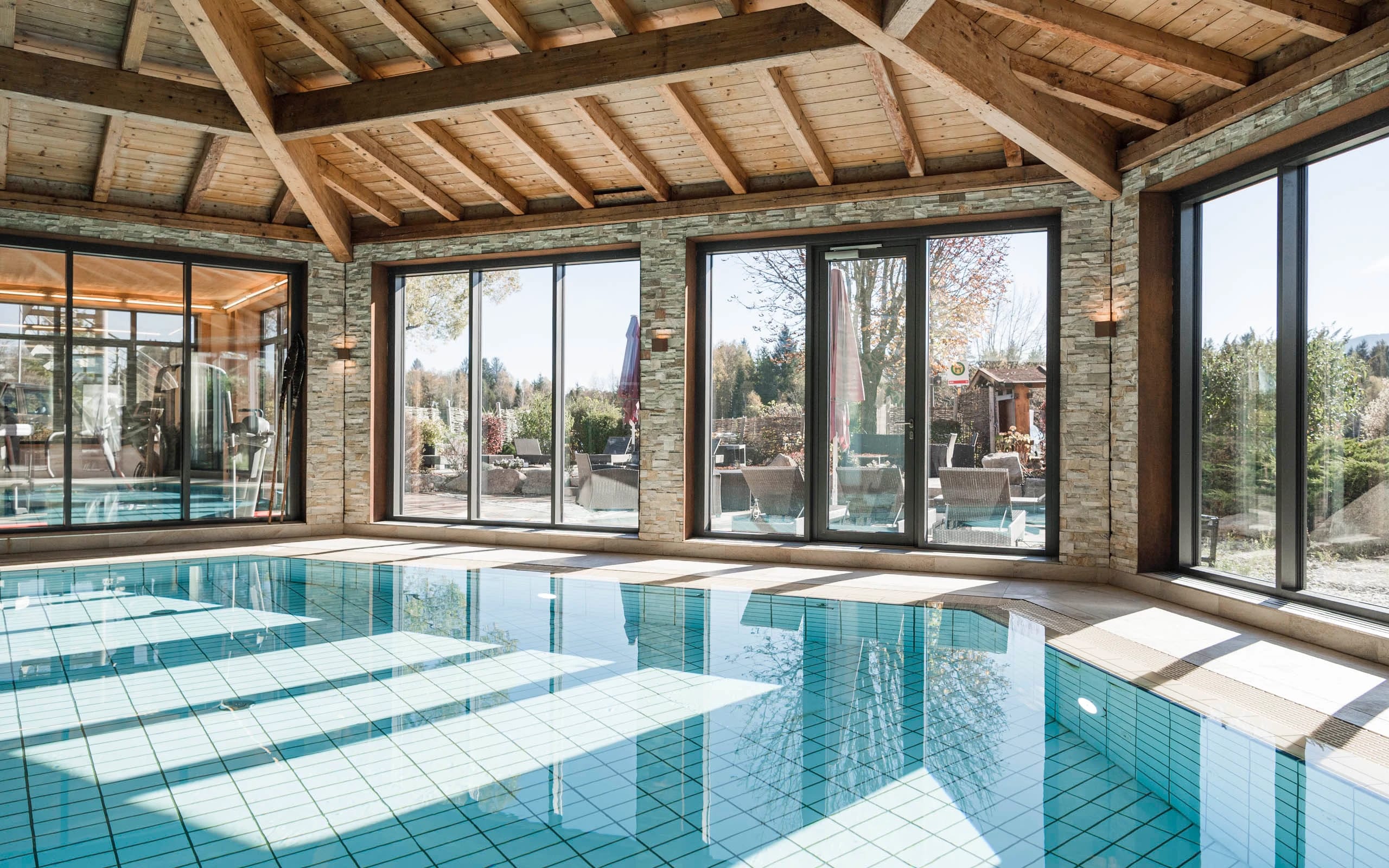 Hallenbad mit Holzbalkendecke und bodentiefen Fenstern zur Terrasse
