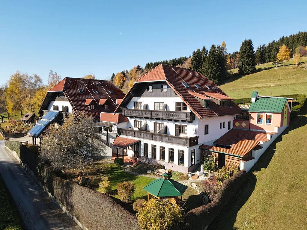 Luftaufnahme des Hauses in herbstlicher Landschaft mit Bergen im Hintergrund