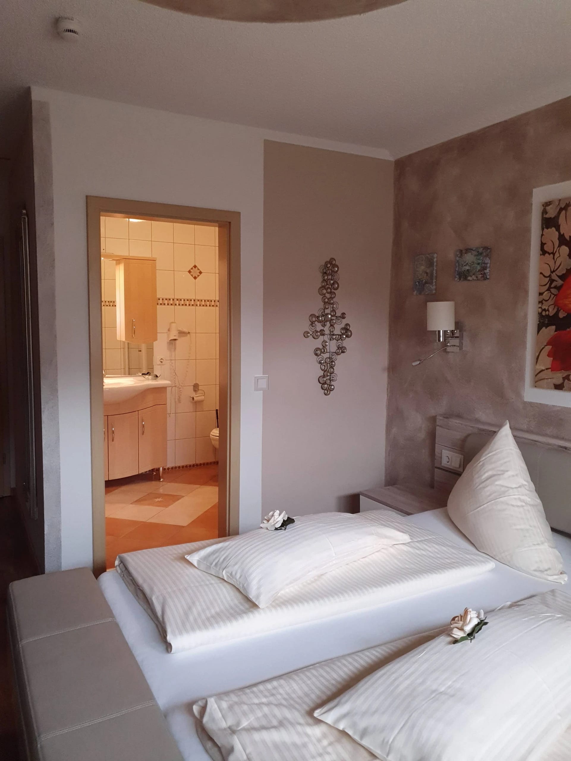 Doppelzimmer mit gemachtem Doppelbett und offenem Blick ins Badezimmer