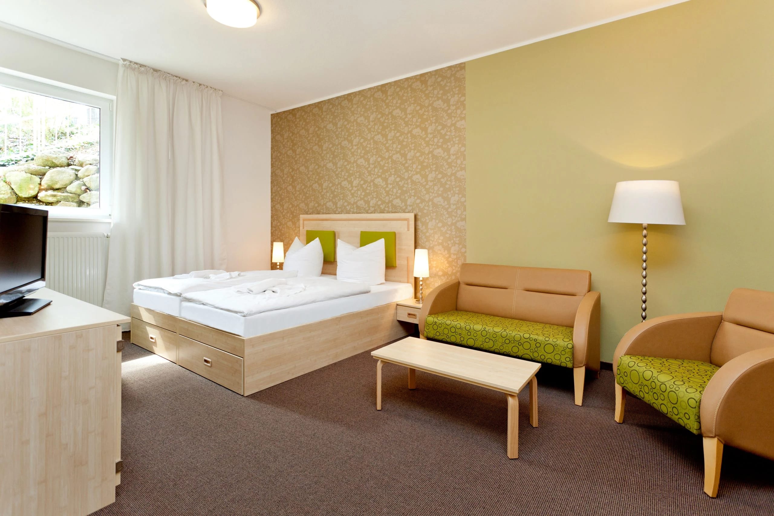 Familienzimmer mit Doppelbett, Sitzecke und grünen Sesseln