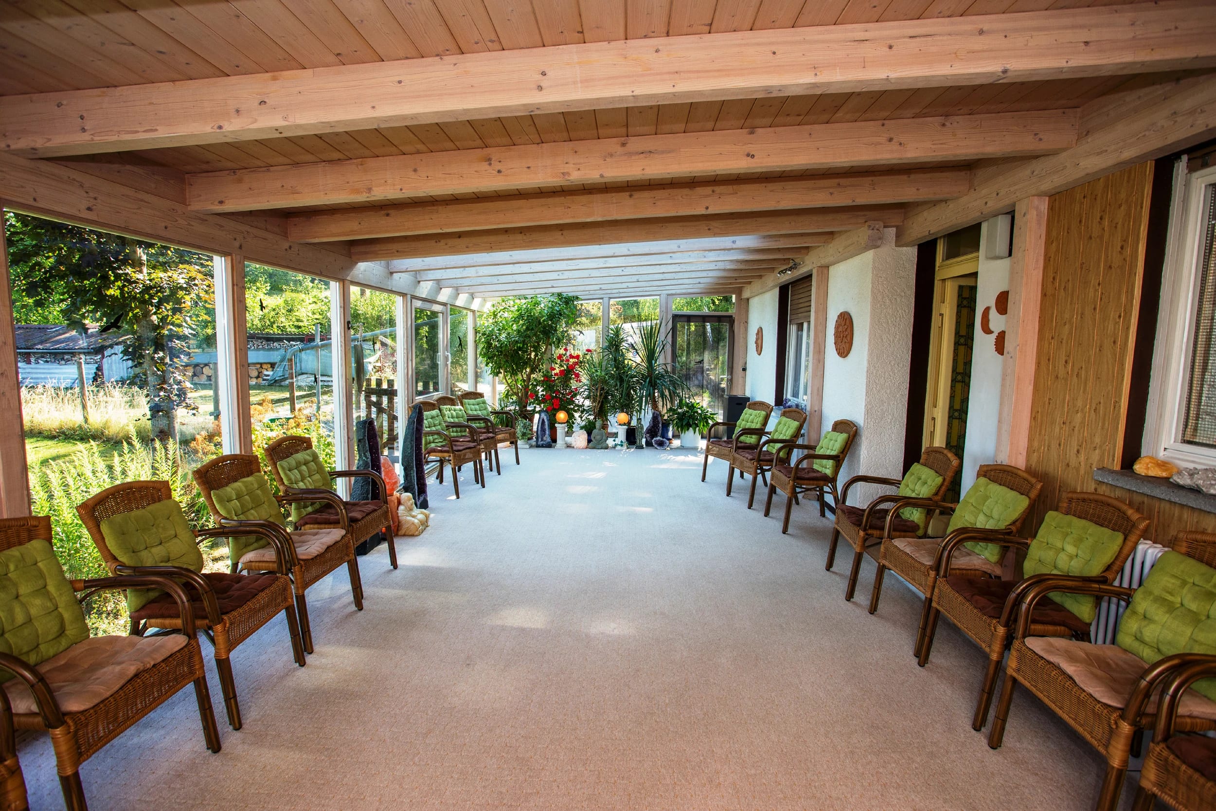Überdachte Terrasse mit Holzdecke, Korbsesseln und Blick in den Garten