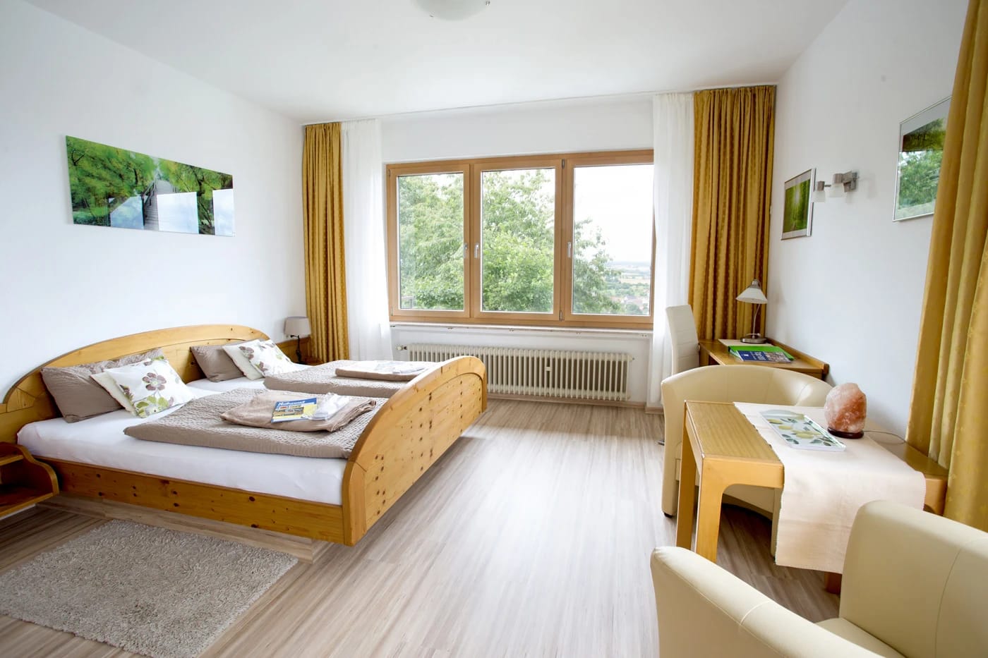 Helles Doppelzimmer mit Holzbett, großem Fenster und Sitzecke