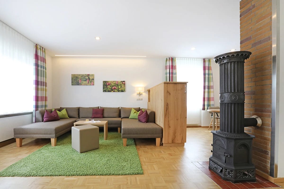 Wohnzimmer im Gästehaus mit Ecksofa, Kaminofen und Parkettboden