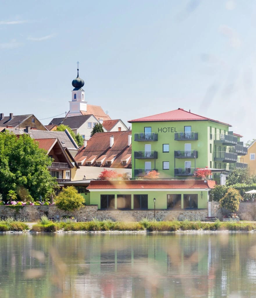 Blick über den Fluss auf das Hotel und die dahinterliegende Altstadt mit Kirchturm