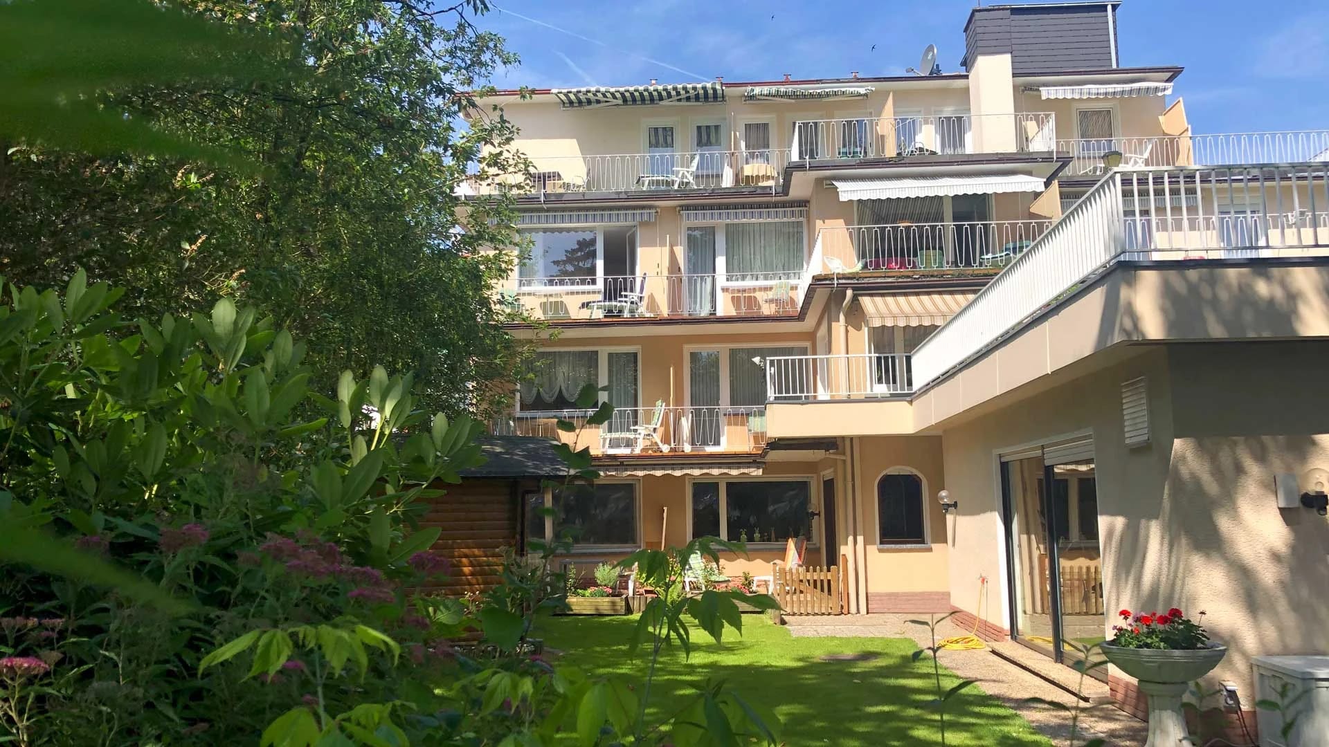Rückansicht des Hotels mit Poolanbau, Terrassenmöbeln und gepflegtem Garten