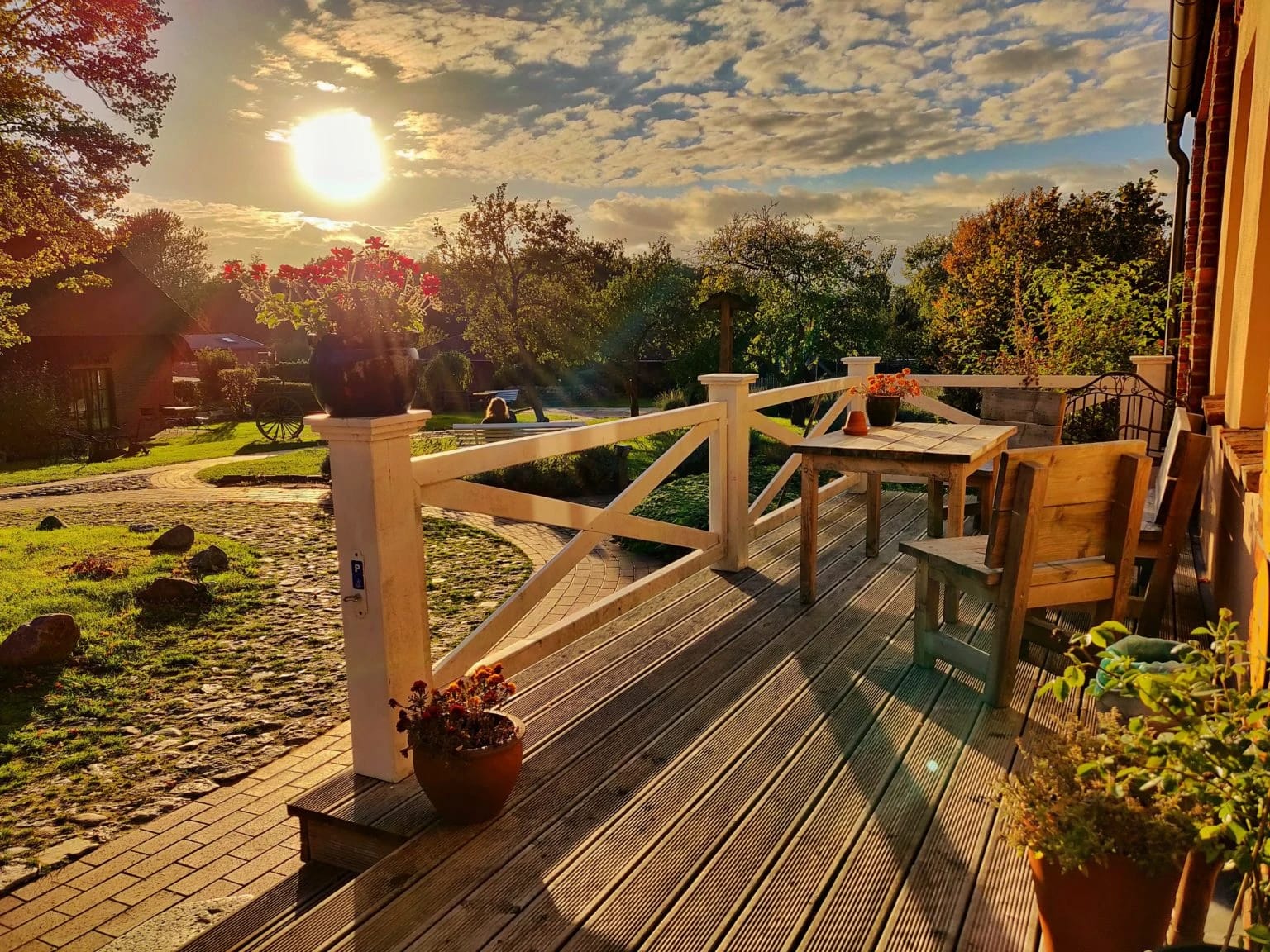 Holzterrasse mit Tisch und Stühlen im Abendlicht, Blick in den Garten