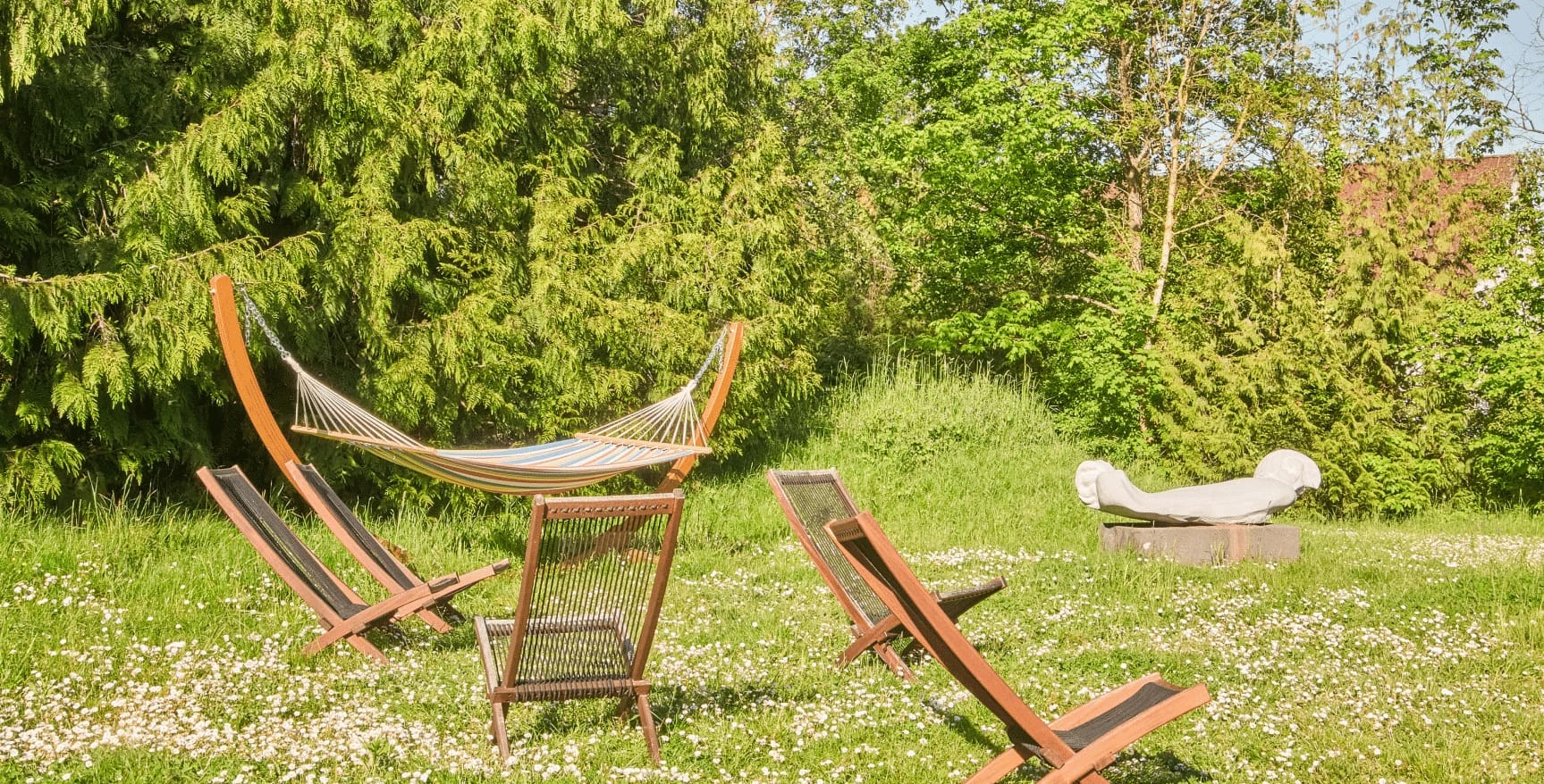 Gartenwiese mit Hängematte und Liegestühlen zwischen Blumen
