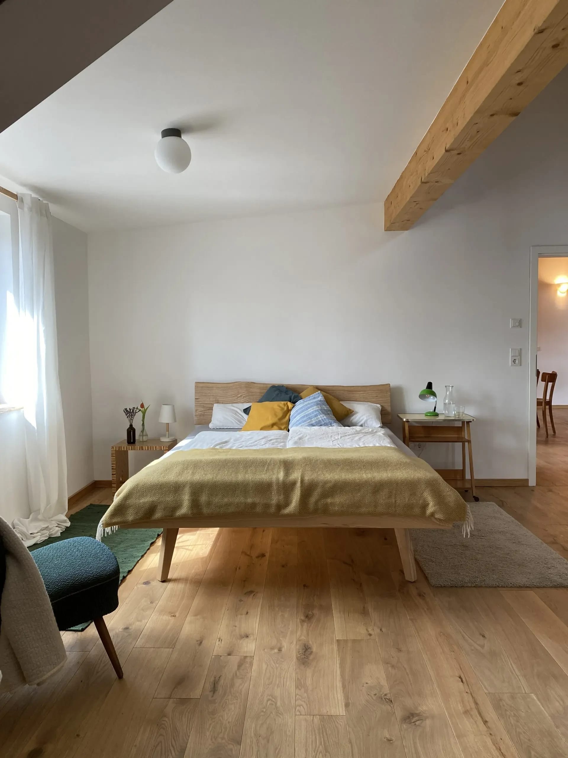 Helles Gästezimmer mit Doppelbett, Holzbalken und Dielenboden