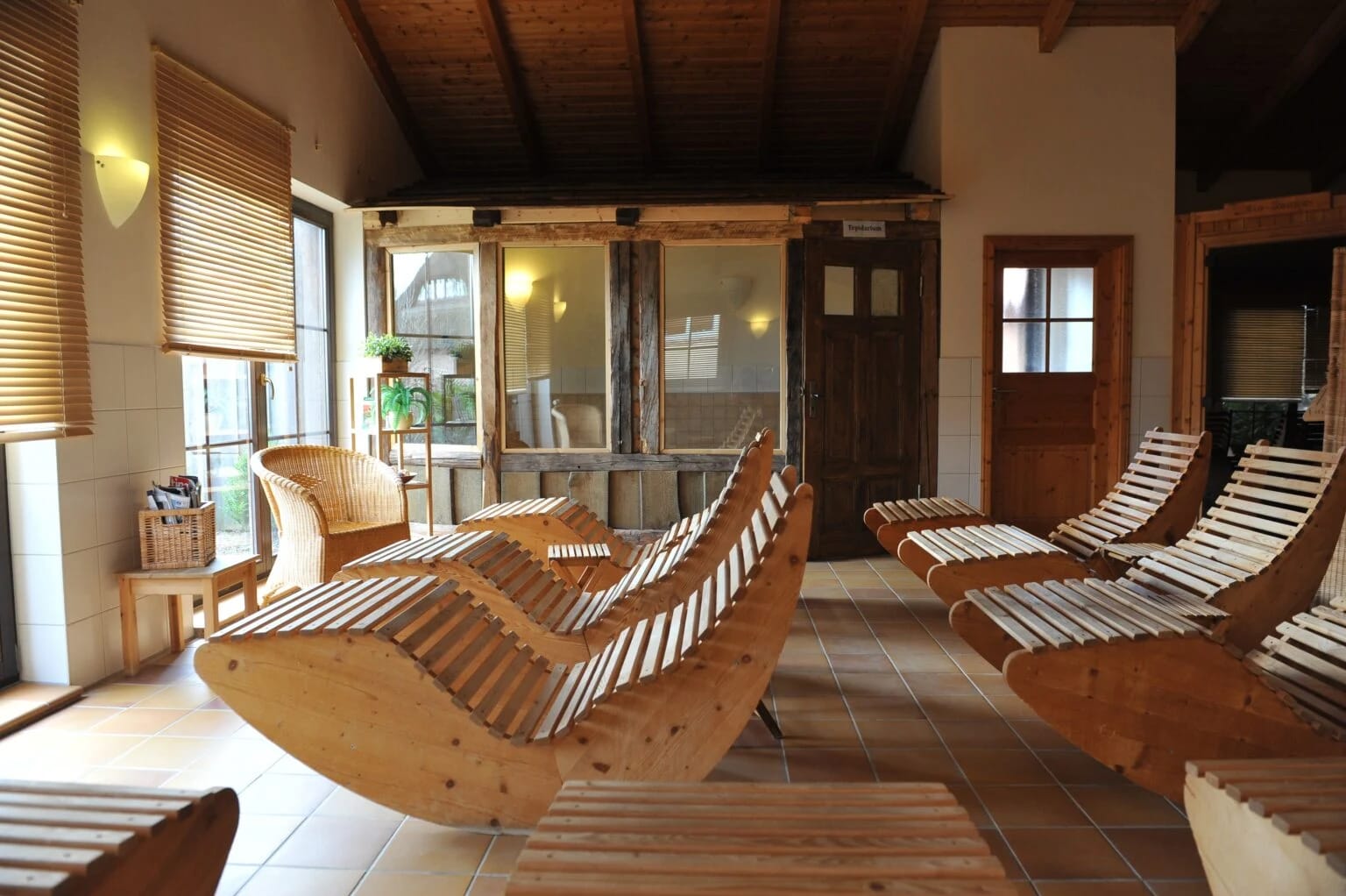 Ruheraum im Saunahaus mit hölzernen Relaxliegen unter offenem Holzdach