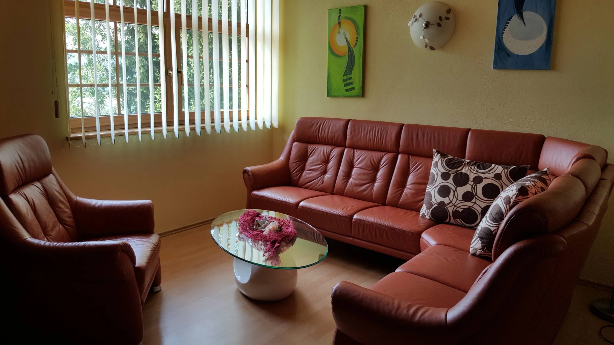 Wohnbereich der Suite mit braunem Ledersofa, Sesseln und Glastisch