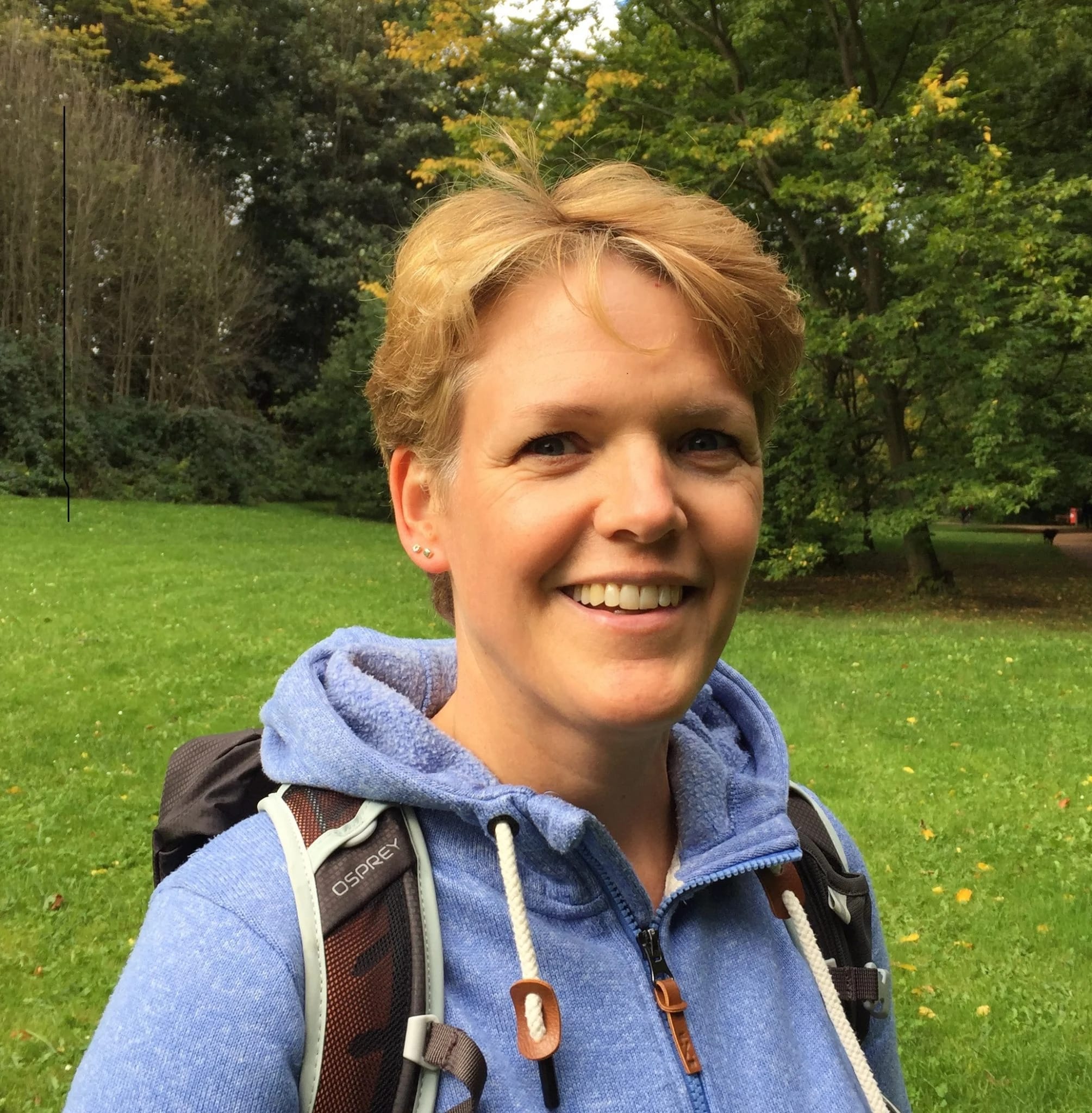 Porträt von Anja Bartsch mit Wanderrucksack im Grünen