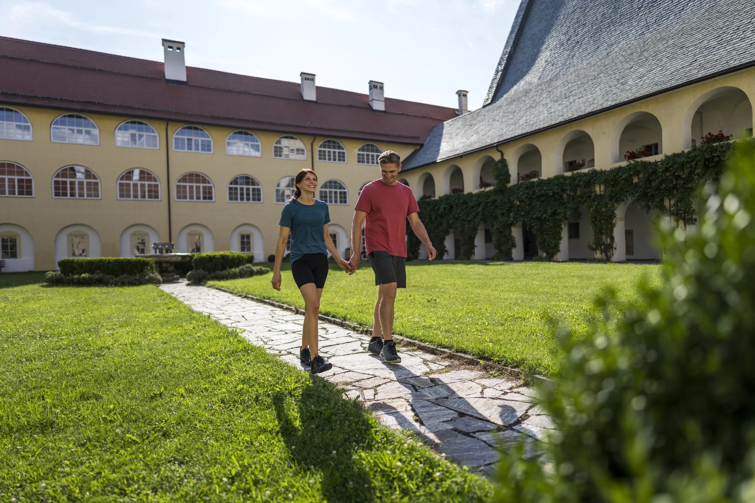 Paar spaziert auf dem Steinweg durch den Innenhof zwischen den Arkadengängen des Stifts