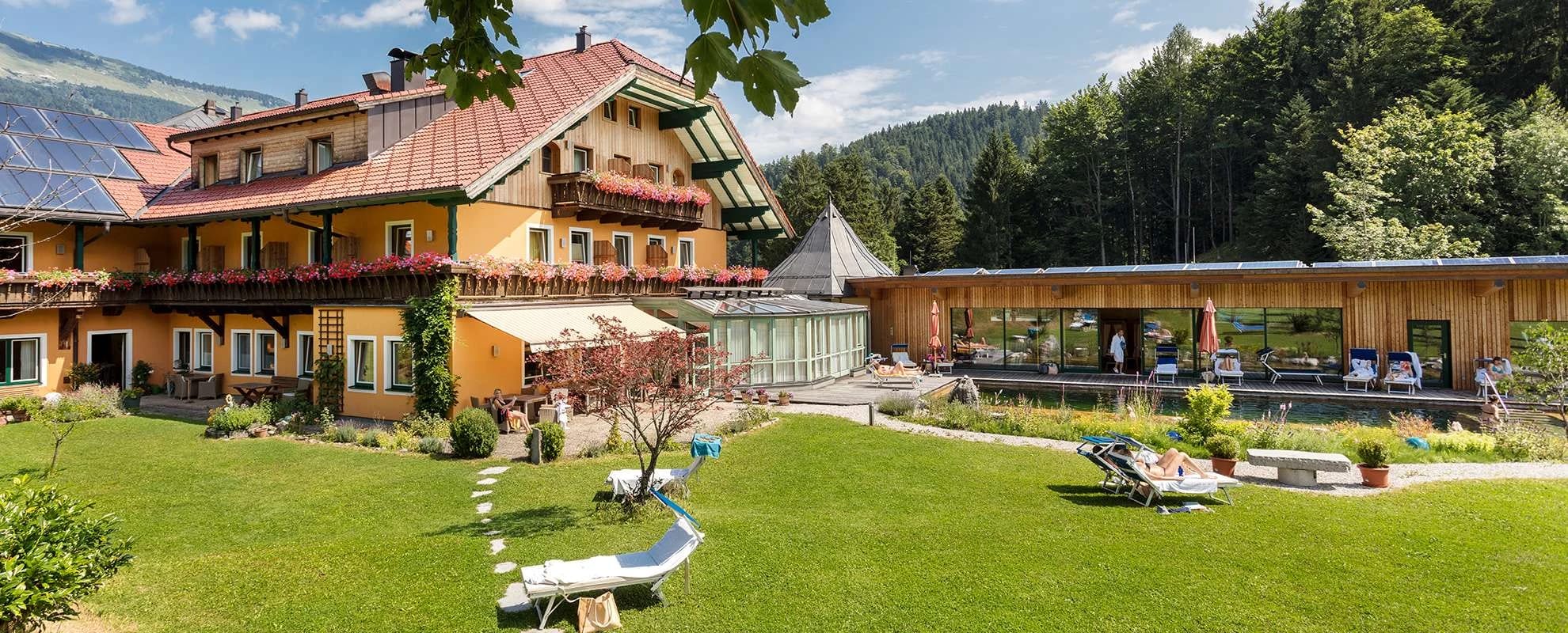 Hausfassade mit Garten, Liegewiese und vorgelagertem Wellnesstrakt