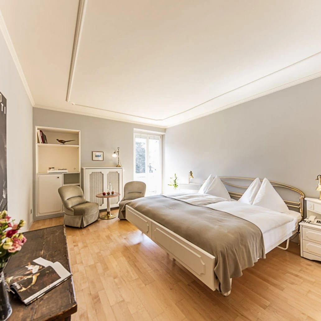 Helles Doppelzimmer mit Parkettboden, breitem Bett, Sessel und eingebauter Schreibnische