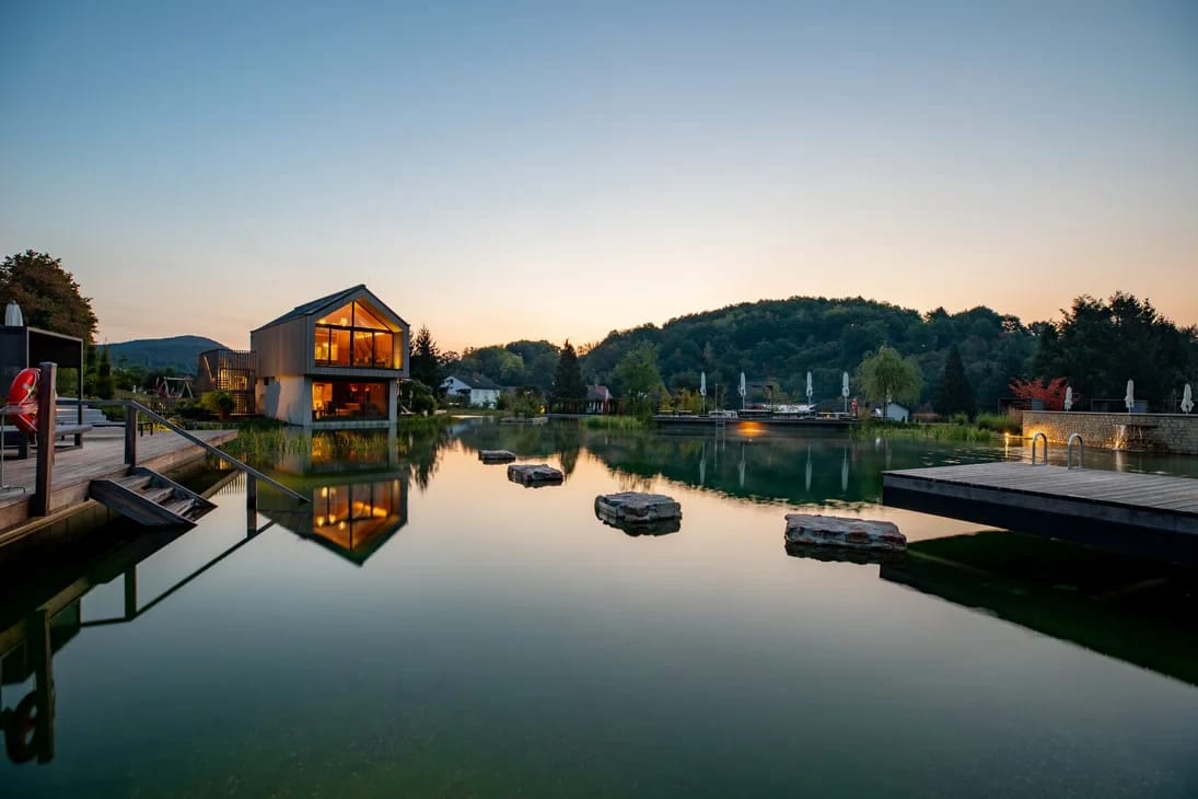 Beleuchtetes Spa-Gebäude am ruhigen Teich in der Abenddämmerung
