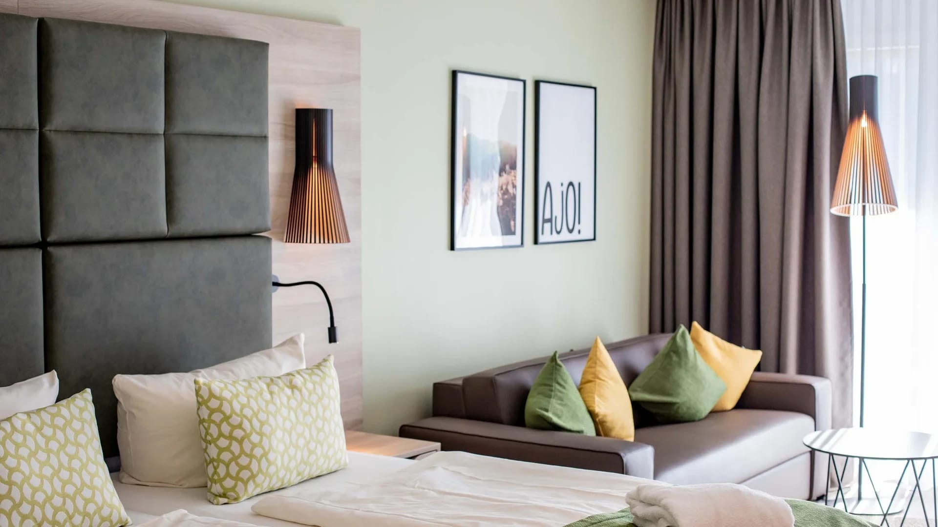 Helles Zimmer mit Doppelbett, Sofa und farbigen Kissen