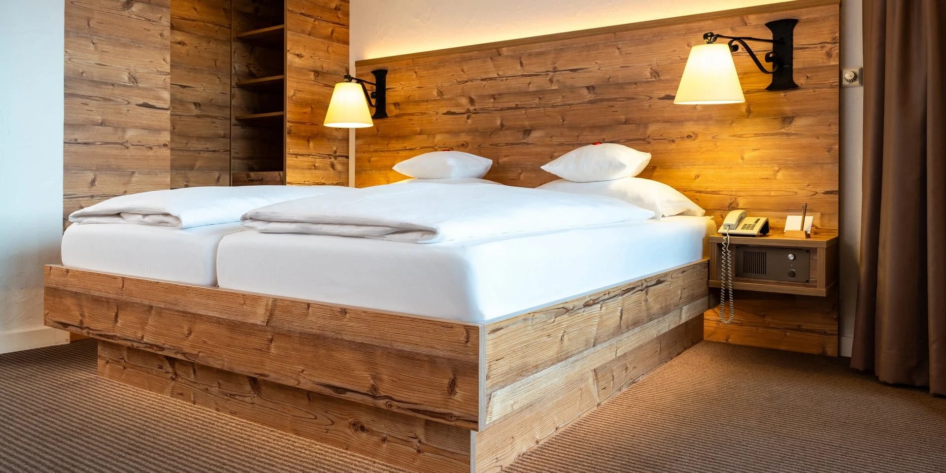 Doppelbett mit Altholz-Kopfteil und zwei Wandleuchten im Doppelzimmer