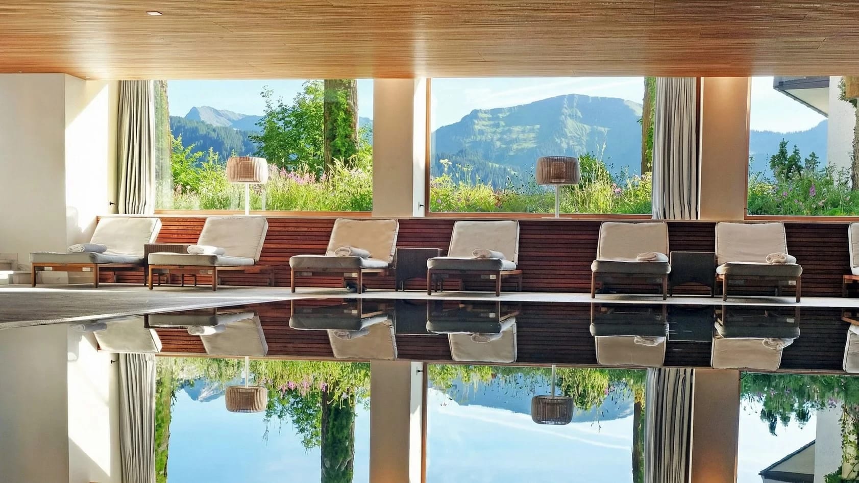 Innenpool mit Holzdecke, Liegen am Beckenrand und Panoramafenstern mit Blick auf die Berge