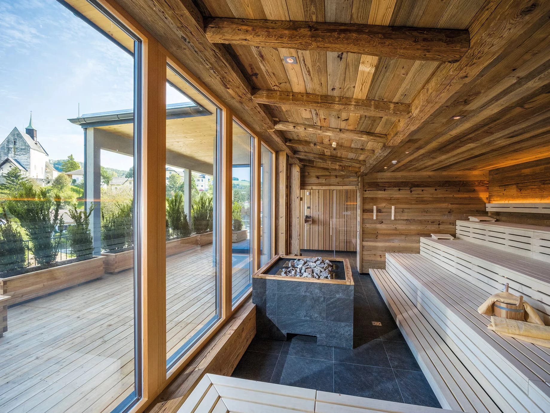 Altholzsauna mit Holzverkleidung und Panoramafenster mit Blick auf die Terrasse