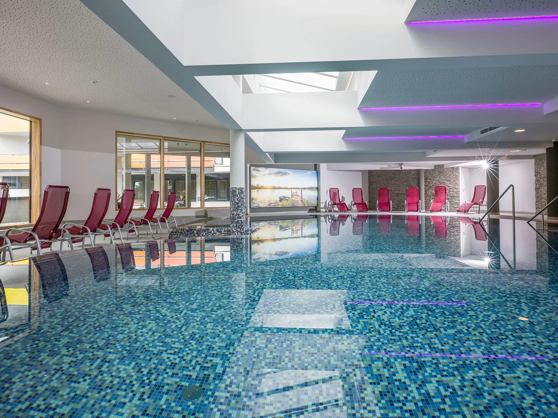 Hallenbad mit roten Relaxliegen und blauen Mosaikfliesen
