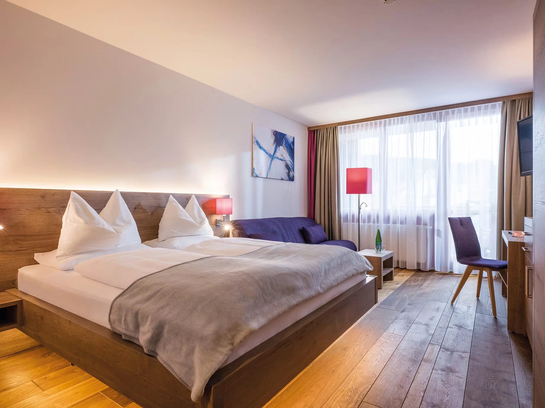 Doppelzimmer mit Bett, Sofa und Sitzecke am Fenster