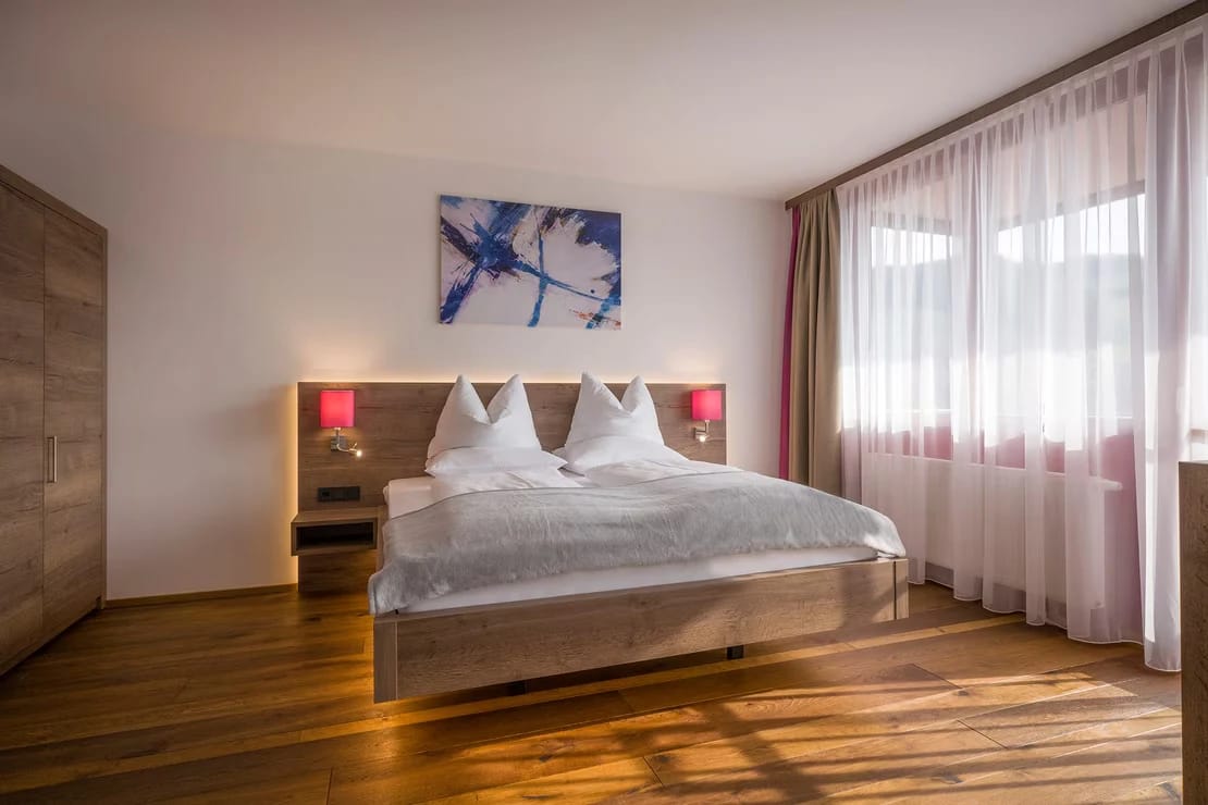 Helles Doppelzimmer mit Doppelbett und bodentiefem Fenster